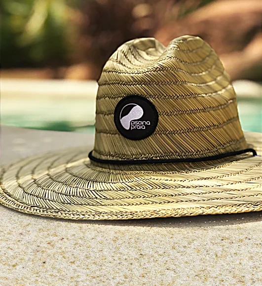 Chapéu de palha com a marca PiscinaPraia na beira da piscina