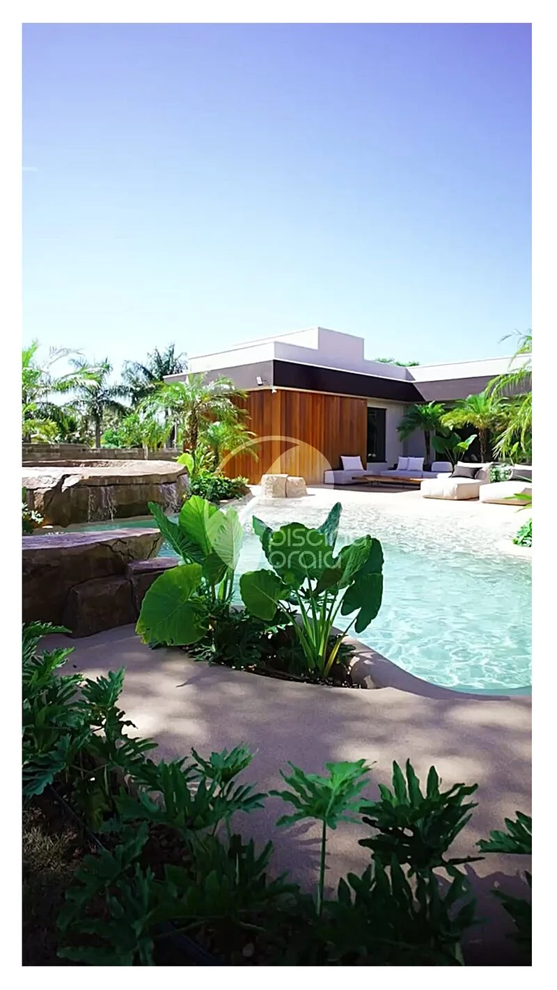 Piscina orgânica com jardim tropical, rochas e área de estar ao ar livre