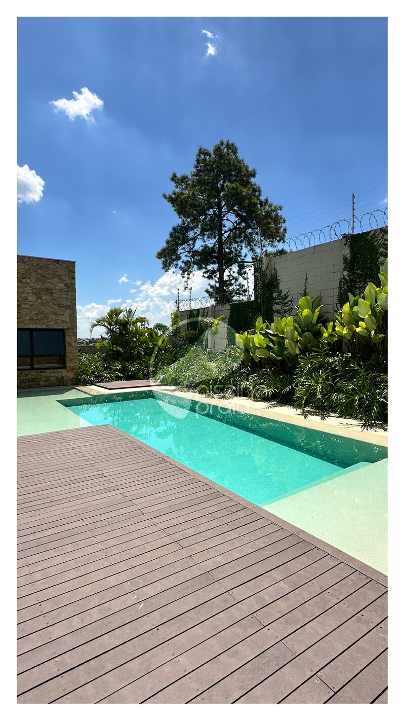 Piscina alongada com deck de madeira e vegetação ao redor