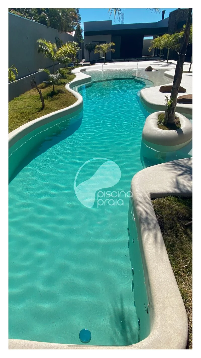 Piscina longa com ilha de coqueiro e jardim junto ao muro
