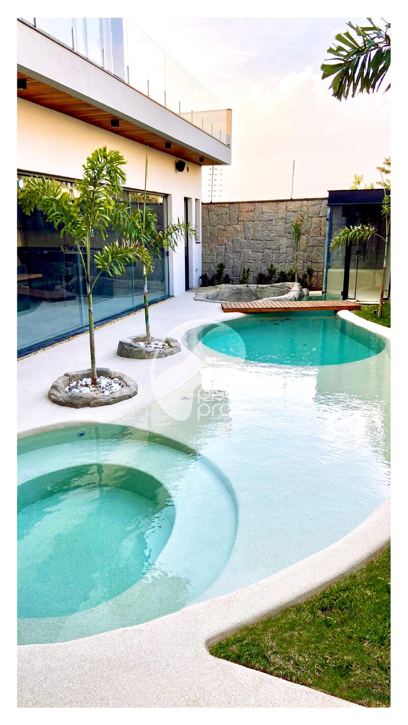 Piscina residencial com hidromassagem, ilhas de coqueiro e deck