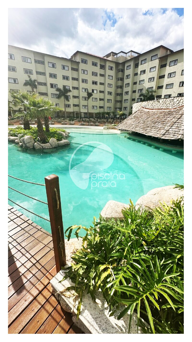 Piscina de condomínio com quiosque de palha, deck e vegetação